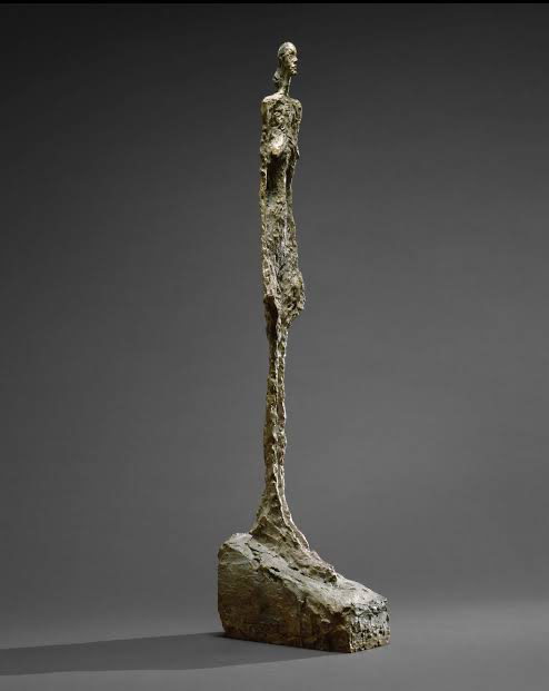 Alberto Giacometti — a tall, slender bronze figure standing on a wedge-shaped base.