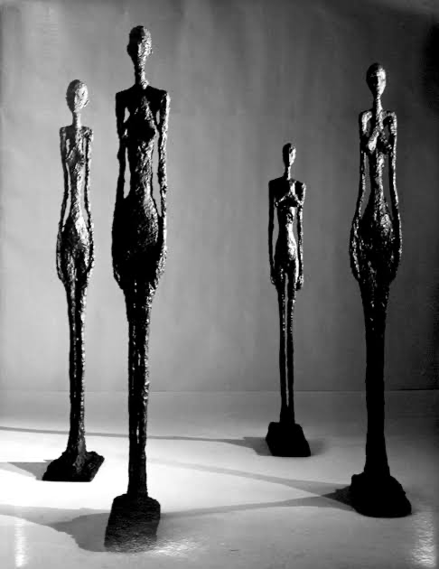 Alberto Giacometti — a group of tall, emaciated bronze figures lit against a dark ground.